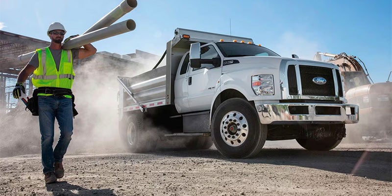 Ford truck at construction site with worker carrying equipment
