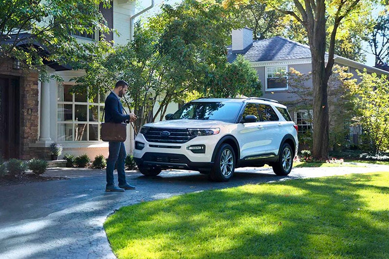 a man standing near parked white Ford car.