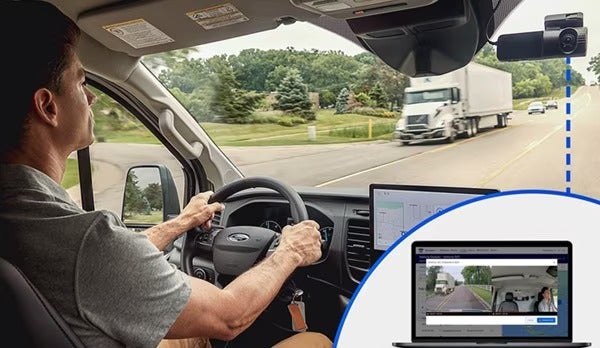 Driver operating Ford vehicle with dashcam footage displayed on screen inset.