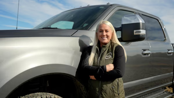 Smiling woman standing beside a gray pickup truck
