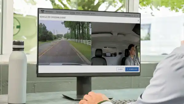 Person reviewing driving footage of speeding event on monitor.