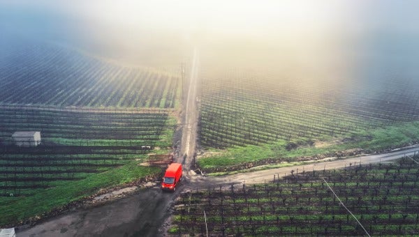 Van driving on rural road beside fields.